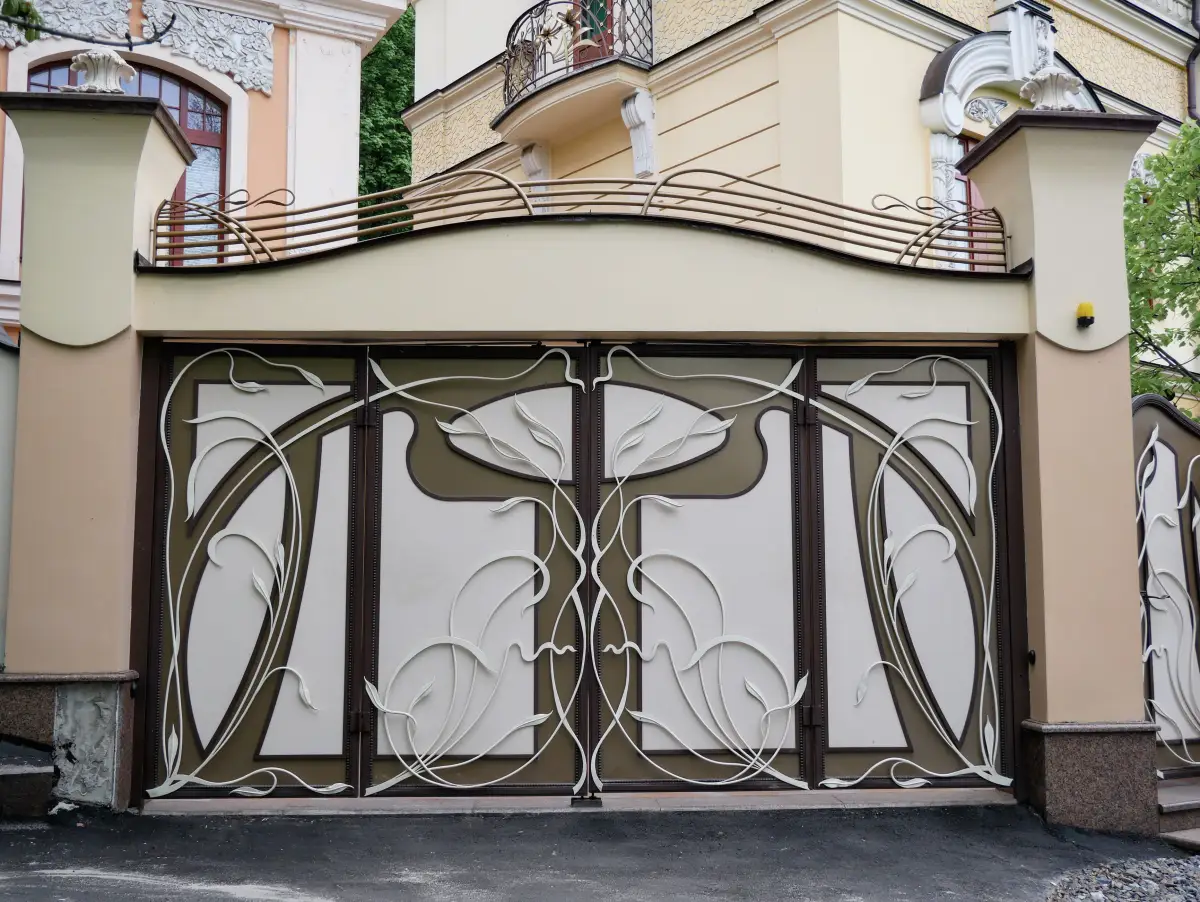 A double gate with flowing Art Nouveau floral ironwork across both leaves