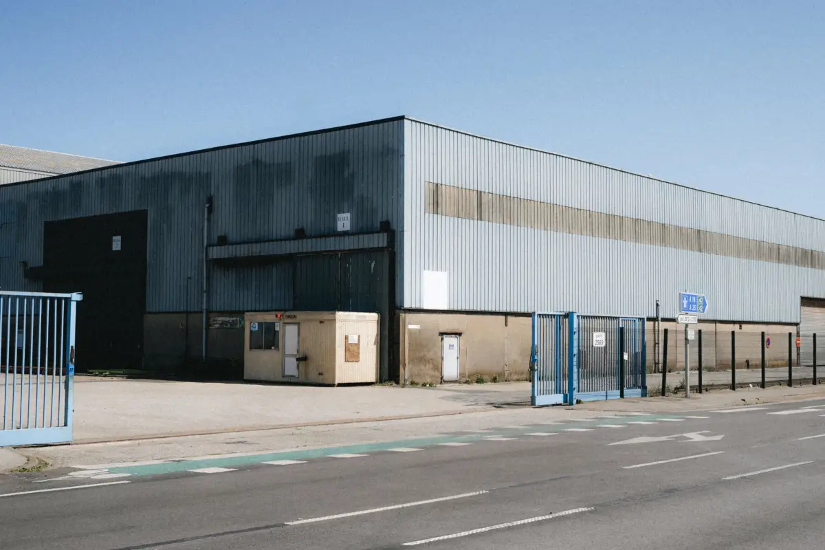 A blue metal gate and fence line across the entrance to a warehouse yard