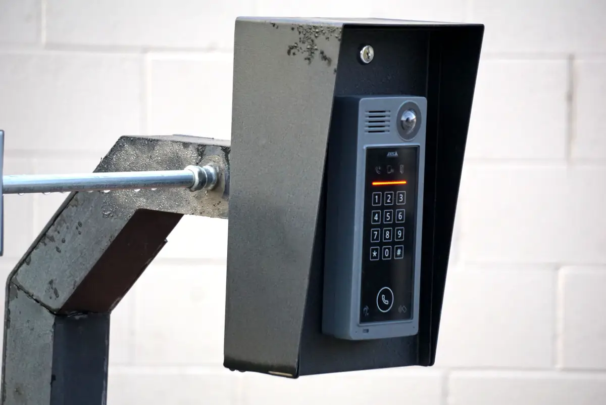 An intercom and keypad unit mounted on a post at a gated entrance