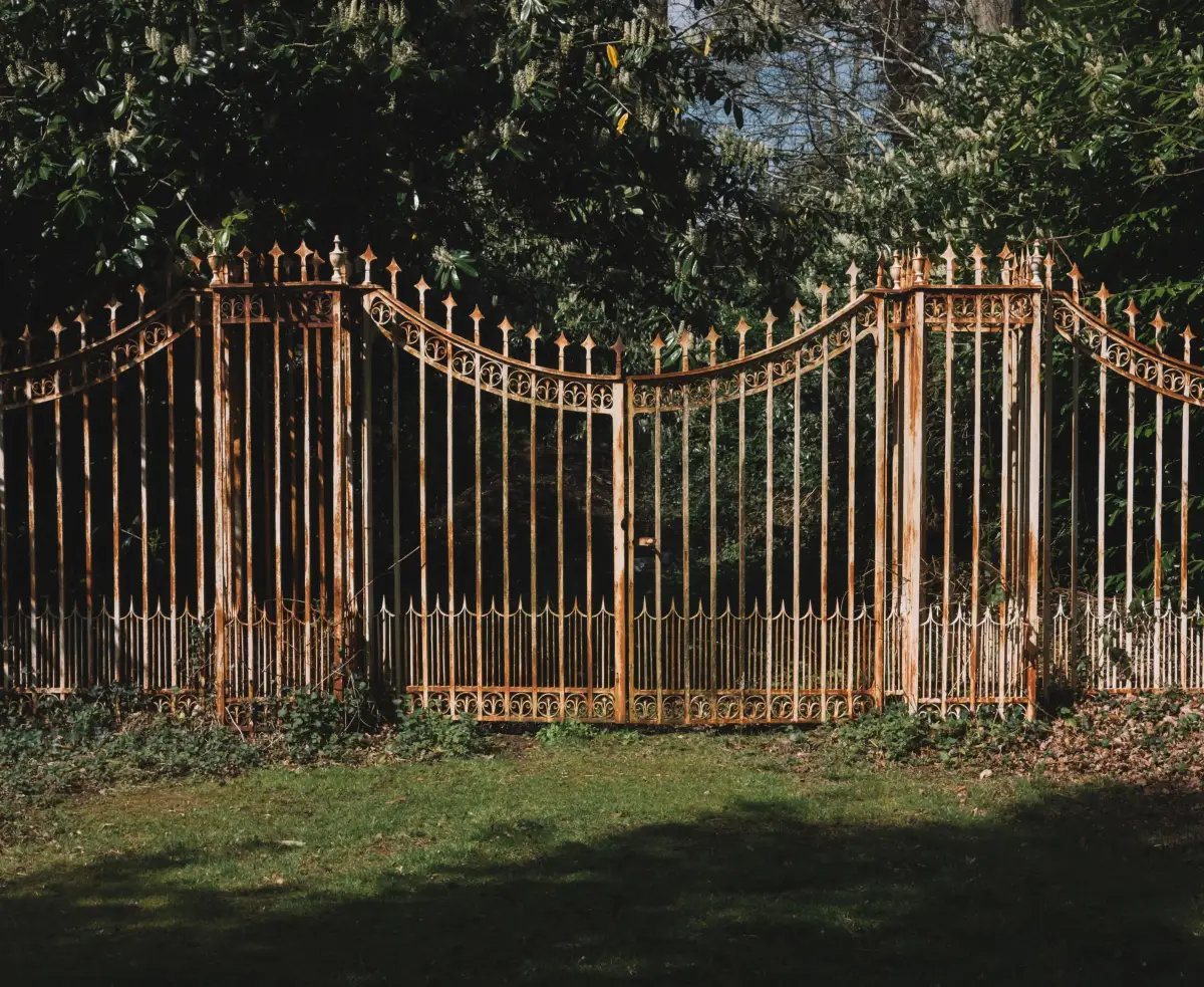 An ornate double swing gate with finial-topped pickets closed across an opening