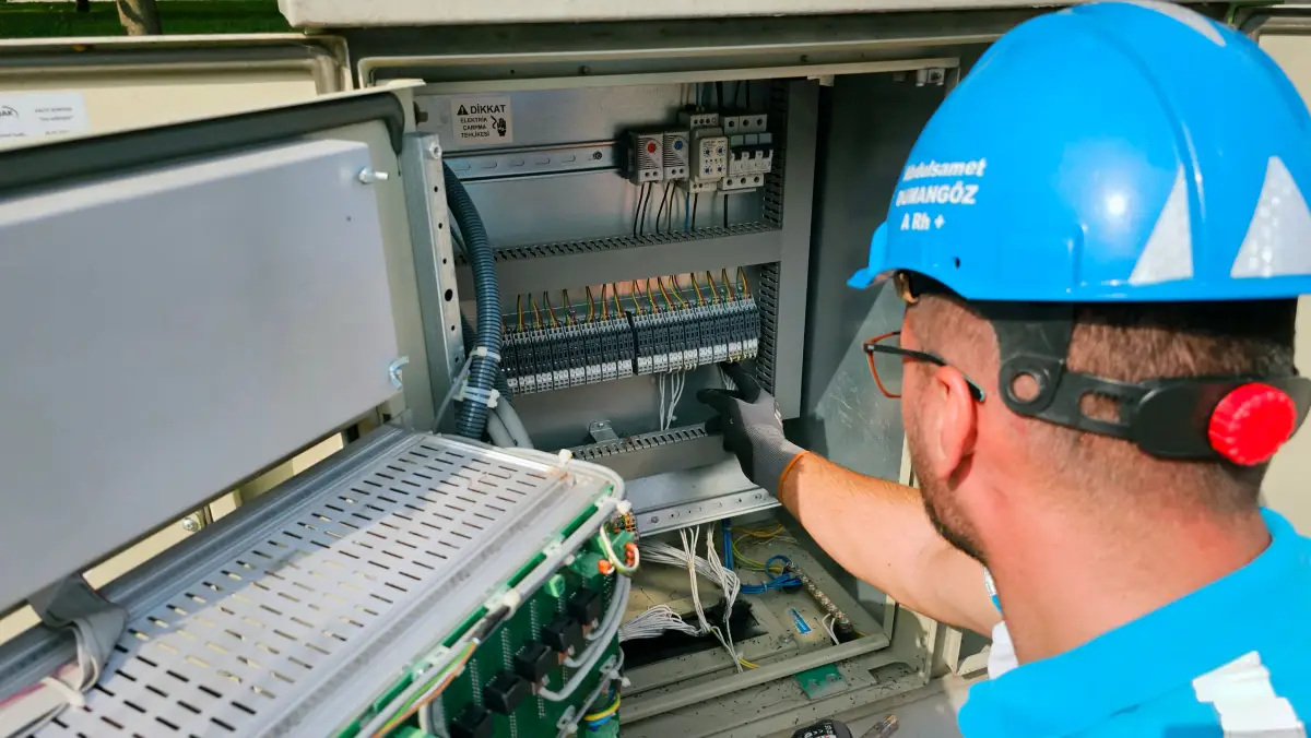 A technician wiring the inside of an outdoor electrical cabinet