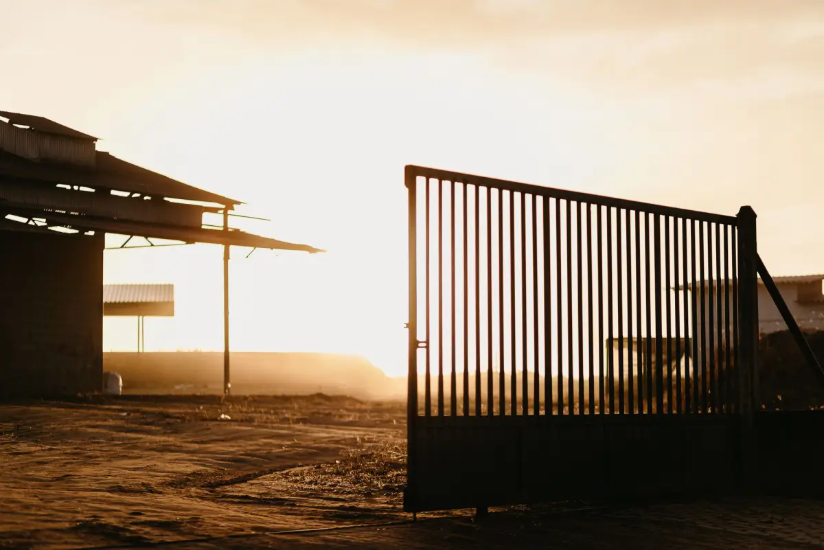 An industrial gate silhouetted against the sky at the end of a shift