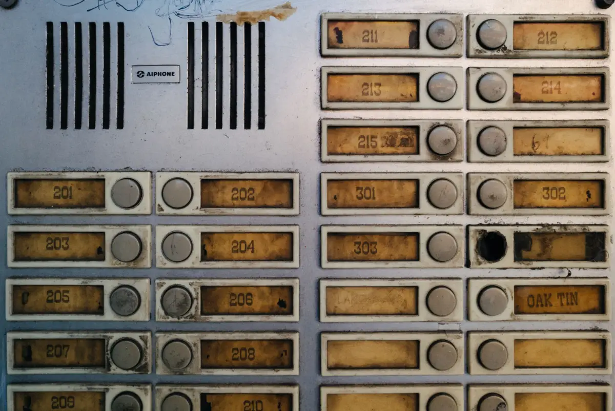 A worn gate intercom and keypad panel at a building entrance