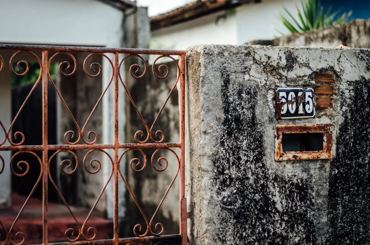 A corroded gate frame mounted against a concrete wall