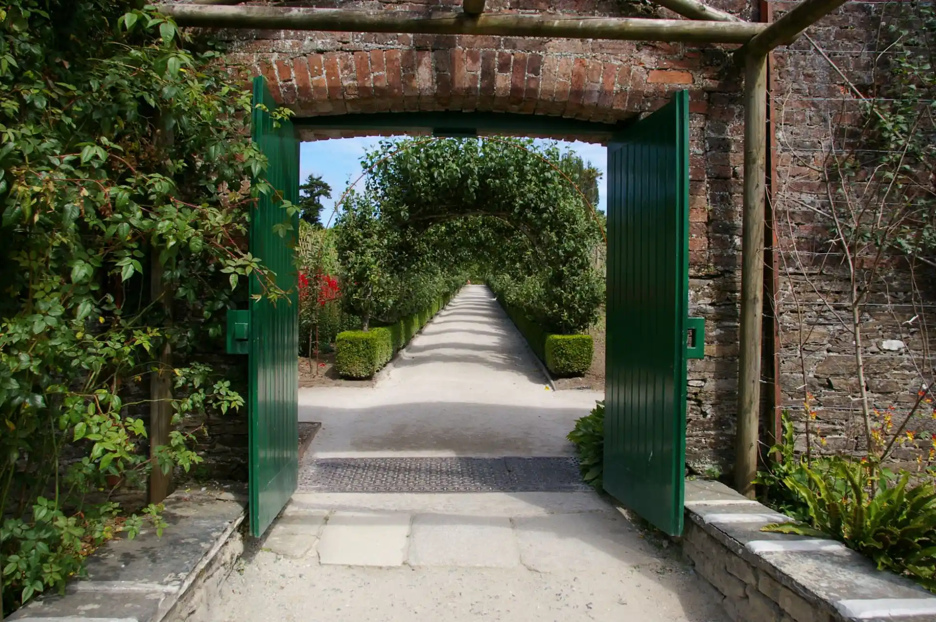 A pedestrian gate standing open onto a planted garden path