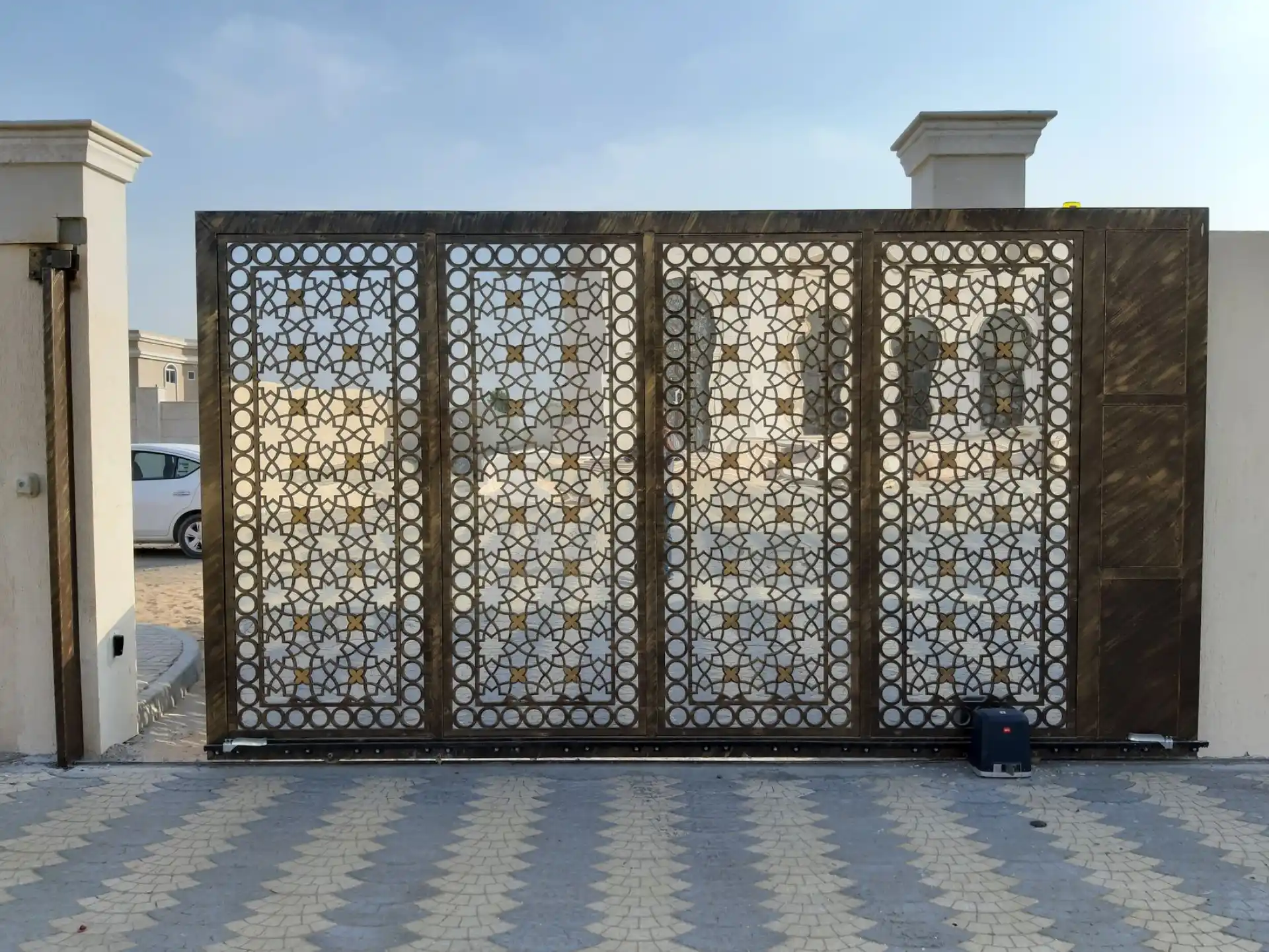A patterned metal sliding gate closed across a property entrance