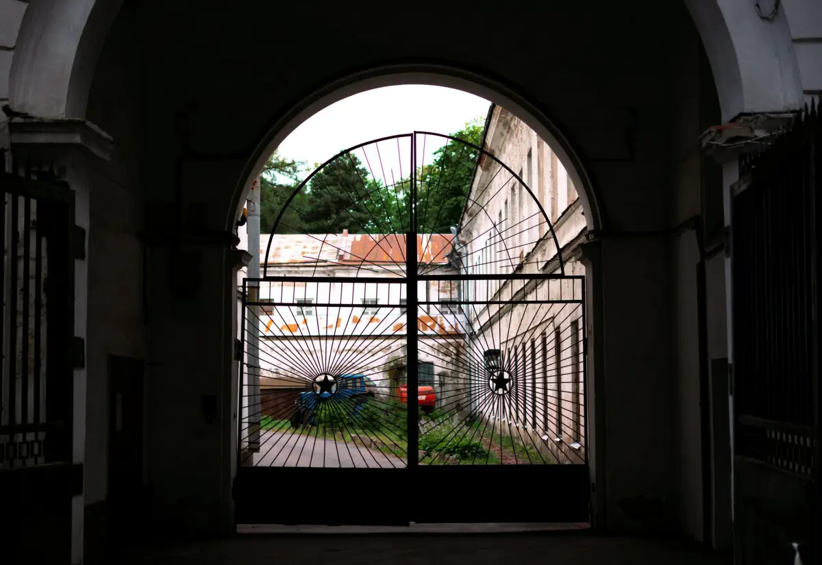 A double swing gate standing open onto a paved courtyard