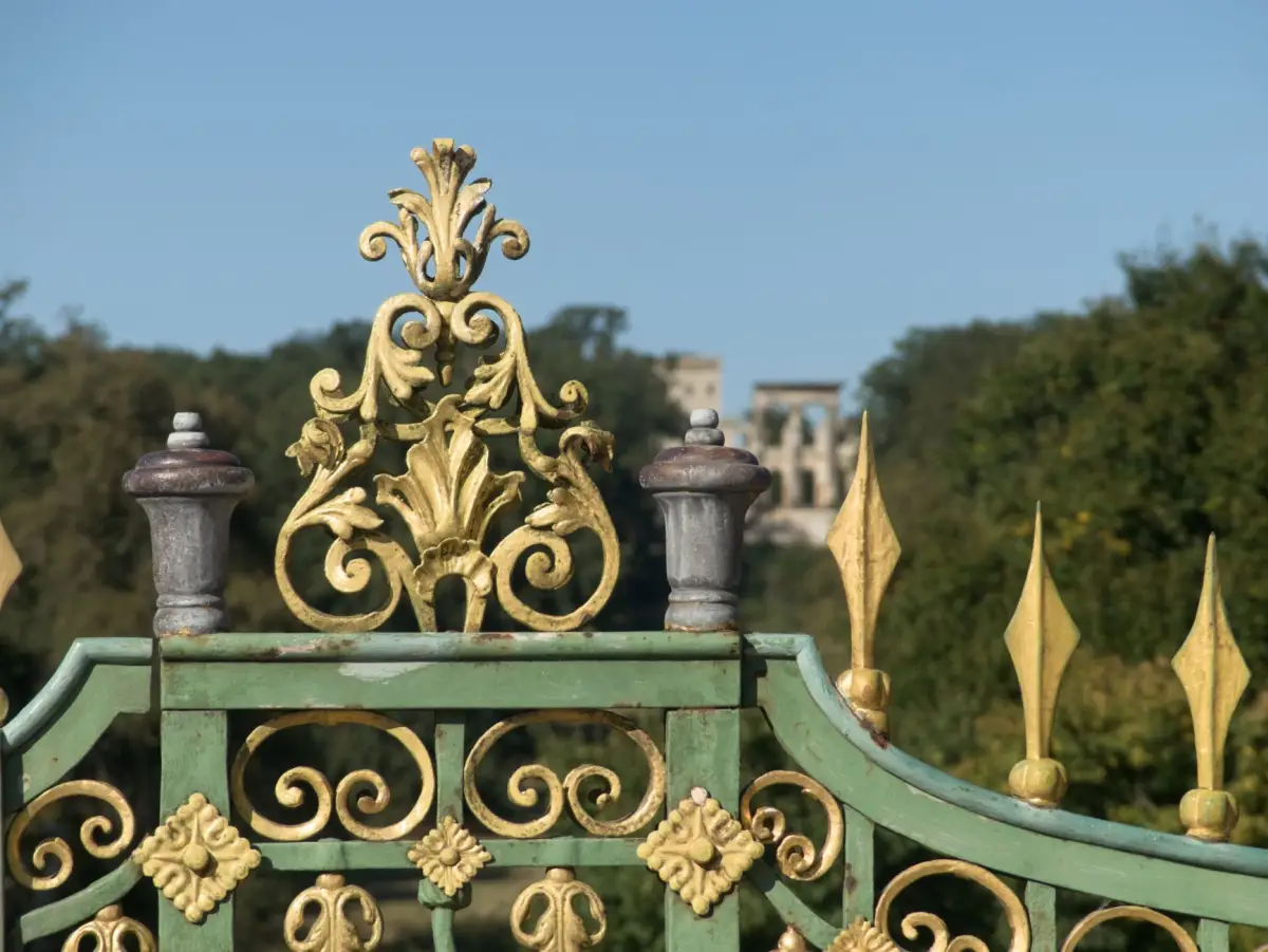 An ornate iron gate with gilded decorative detail